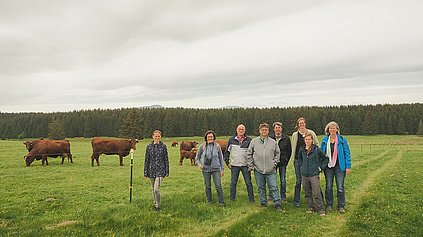 Gruppenbild der Teilnehmenden auf der Weide.Im Hintergrund weiden die Kühe.